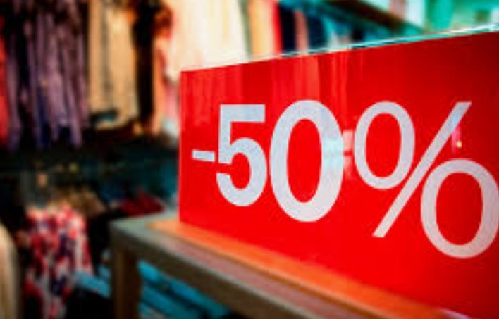Cartel rojo de descuento del 50% sobre un mostrador en una tienda de ropa.