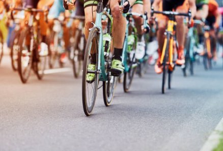 Ciclistas pedaleando en pelotón durante una carrera, primer plano de ruedas y piernas