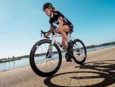 Ciclista en posición aerodinámica sobre bicicleta de triatlón junto al mar